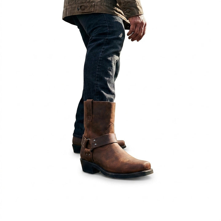 Mann in dunkler Jeans und Jacke trägt den braunen Lederstiefel mit Zierriemen, Ansicht von der Seite im Gehen. 1