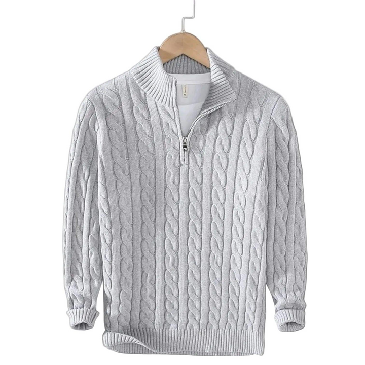 Hellgrauer Zopfstrick-Pullover mit gerippten Bündchen und Stehkragen, auf einem Holzbügel präsentiert, weißes Shirt blitzt am Kragen hervor. 4