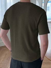 Mann trägt olivgrünes, geripptes T-Shirt, Rückansicht, moderne Herrenmode, lässiger Stil.