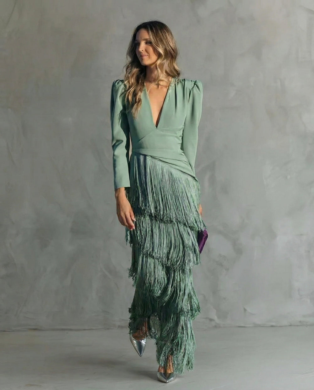 Model in grünem Fransenkleid, leicht seitlich gedreht, in ganzer Figur mit silbernen Pumps und lila Clutch 2