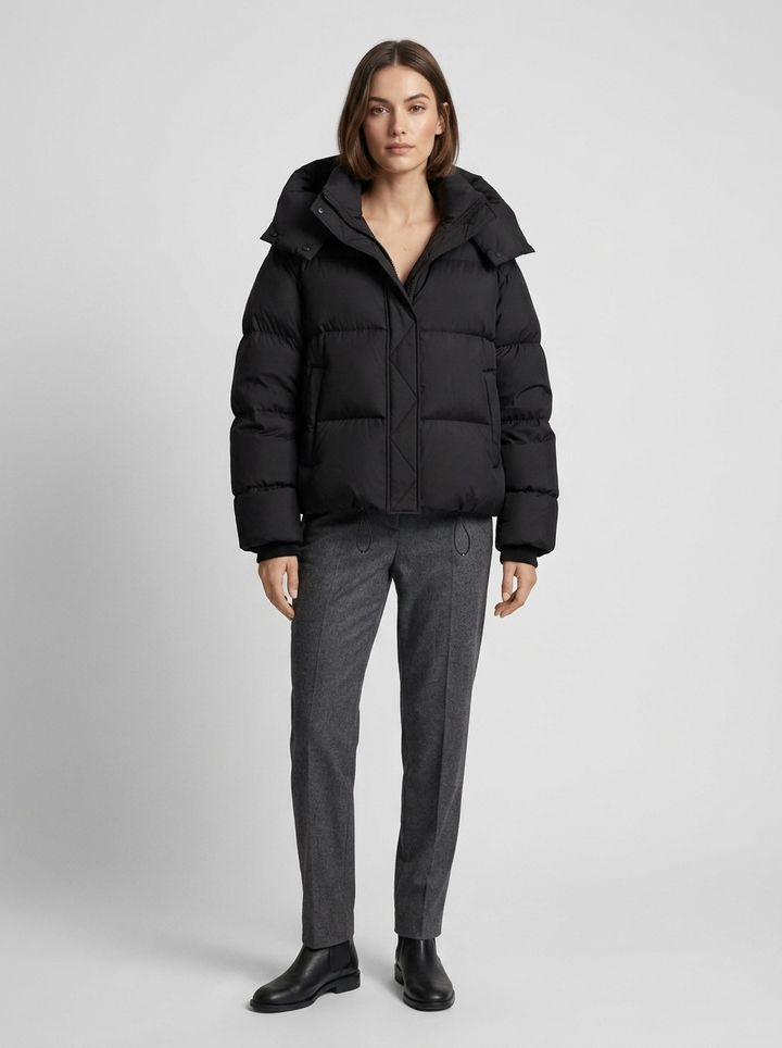 Model trägt die schwarze Steppjacke offen mit grauer Hose und schwarzen Stiefeletten, Ganzkörperansicht 4