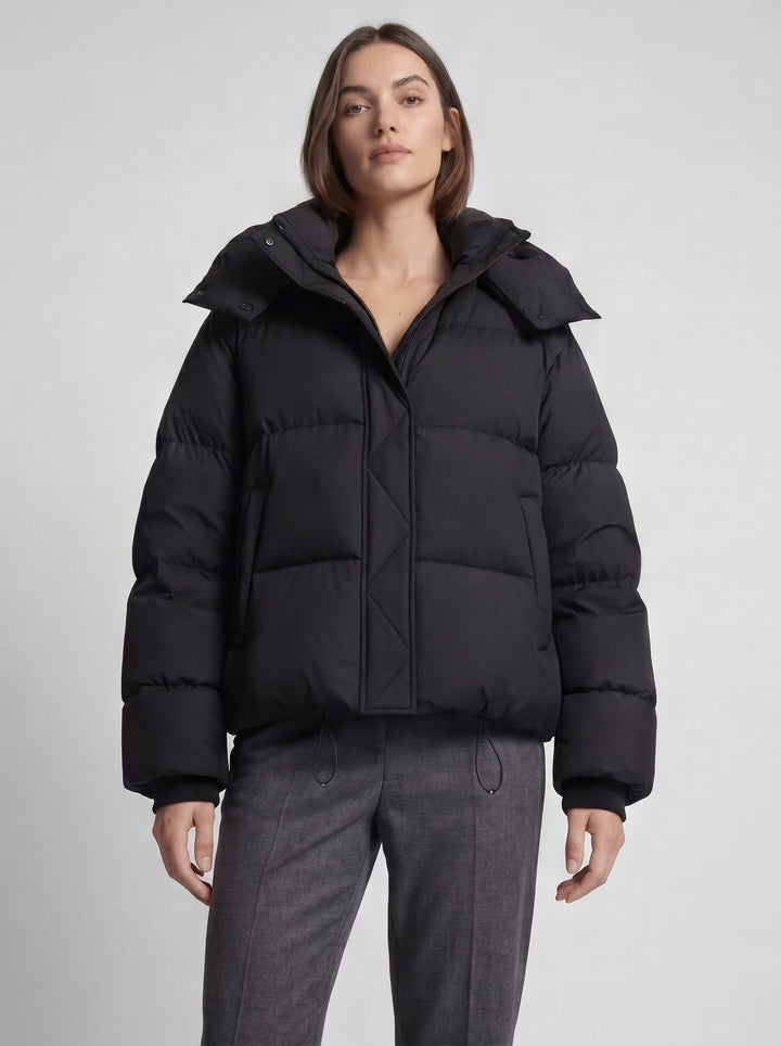 Nahaufnahme des Models in der schwarzen oversized Steppjacke, Oberkörper von vorn mit grauer Hose 6