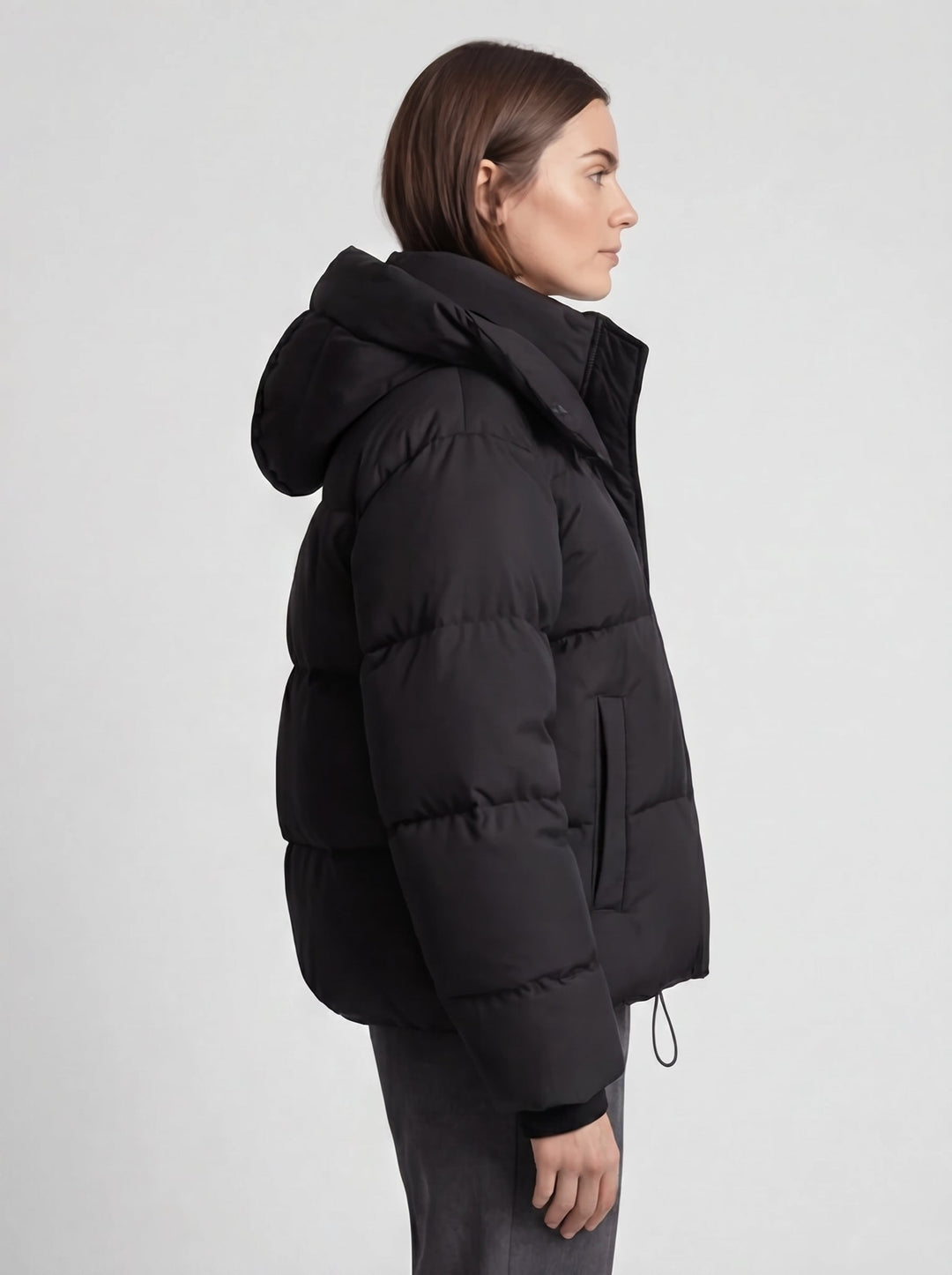 Seitenansicht der schwarzen Steppjacke am Model, Kapuze, Seitentasche und Kordelzug am Saum sichtbar 5