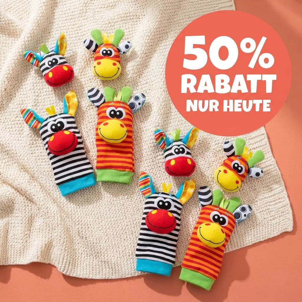 Mehrere Rasselsocken und Handgelenkrasseln mit Zebra- und Giraffengesichtern liegen verteilt auf einer cremefarbenen Strickdecke. 8