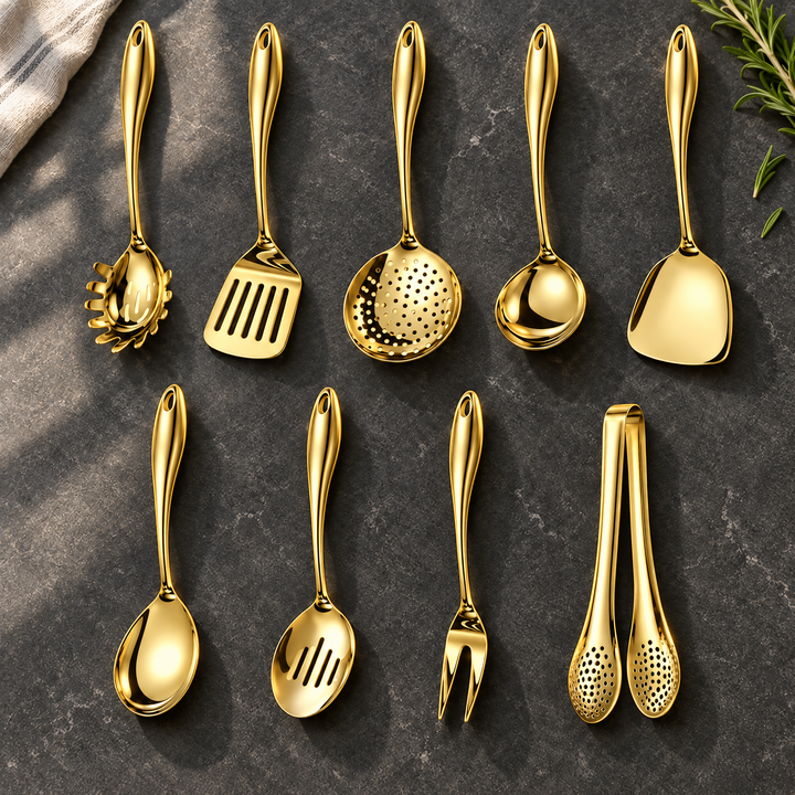 Neunteiliges goldfarbenes Set in zwei Reihen auf dunkler Steinfläche, mit Schaumkelle, Wender, Gabel und Zange, dazu Rosmarin und Leinentuch. 25
