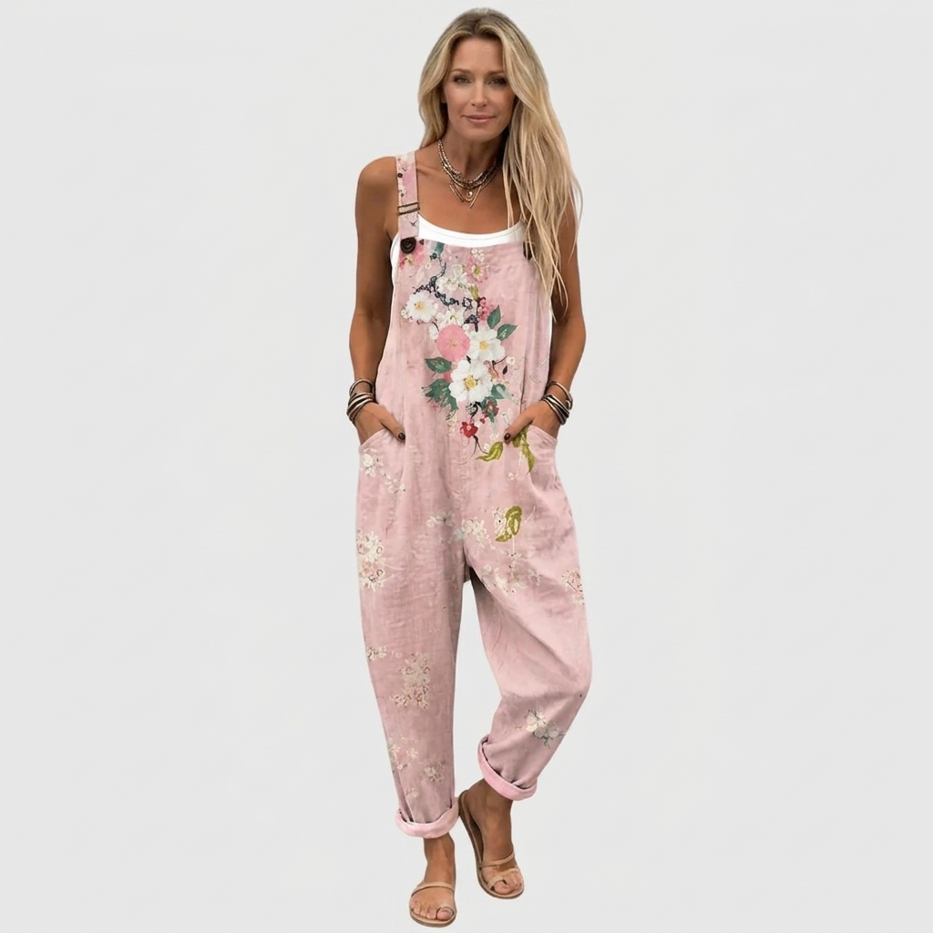 Frontansicht in Ganzkörperaufnahme: Model mit weißem Top unter der Latzhose, Blumenmuster, hochgekrempelte Beine und Sandalen. 2