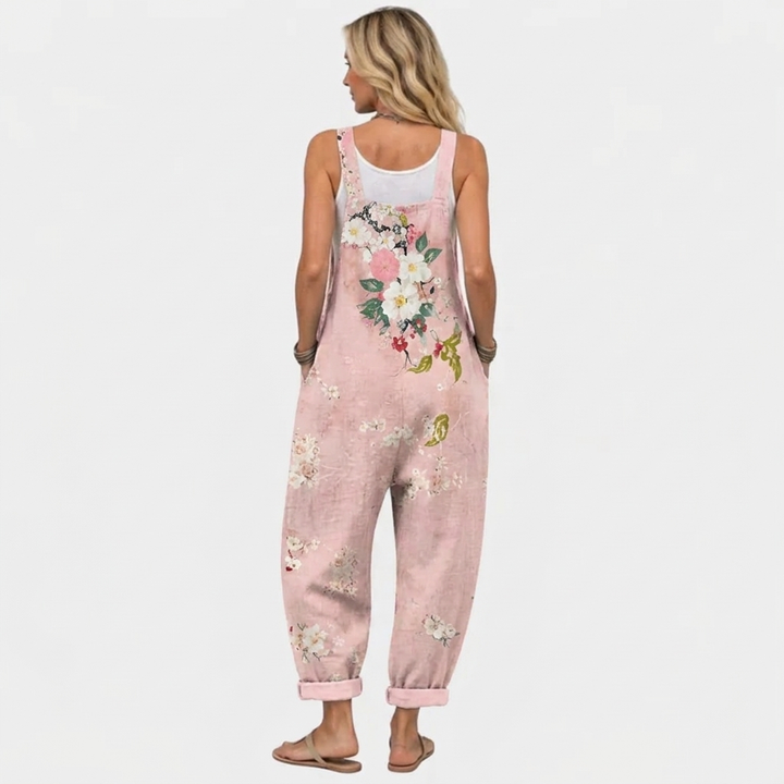 Rückansicht des Models in der Latzhose mit breiten Trägern, großem Blumenmotiv auf dem Rücken und weit geschnittenen Hosenbeinen. 4