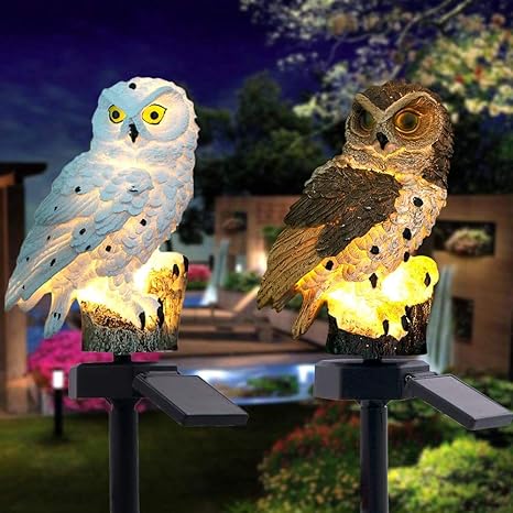 Eine weiße und eine braune Eule leuchten nebeneinander abends im Garten, jeweils mit Solarpanel auf dem Erdspieß. 17
