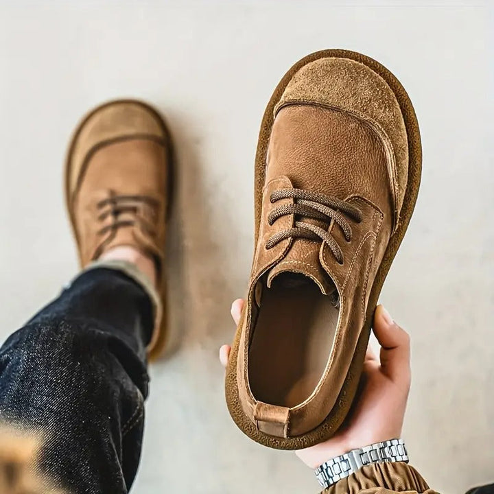Hellbrauner Schuh in der Hand von oben gezeigt, mit Blick ins Innere, im Hintergrund der zweite Schuh am Fuß. 5
