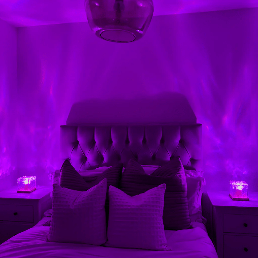 Dasselbe Schlafzimmer in violettes Licht getaucht, zwei Würfellampen auf den Nachttischen werfen fließende Lichtwellen an Wände und Decke. 3