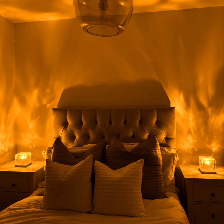 Zwei Würfellampen auf Nachttischen werfen orange Flammenmuster an die Wand über einem gepolsterten Bett mit Kissen. 2