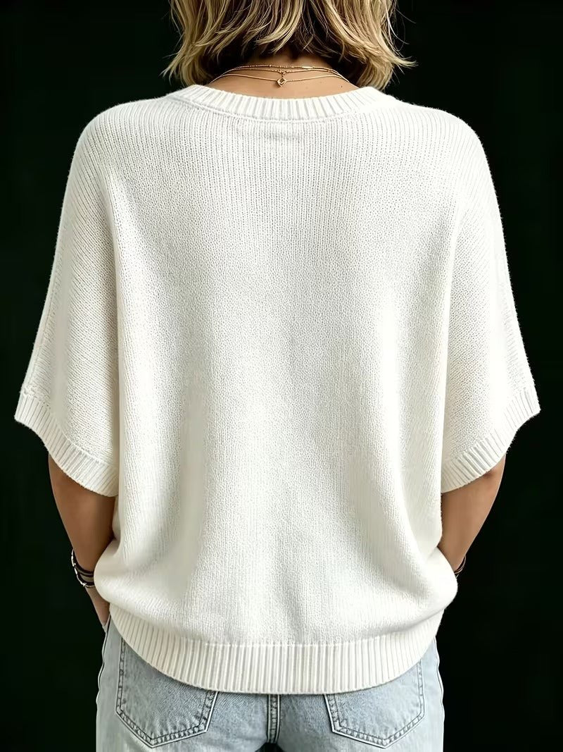 Rückansicht des cremeweißen Strickoberteils mit breiten Rippbündchen an Ärmeln und Saum, kombiniert mit heller Jeans. 25