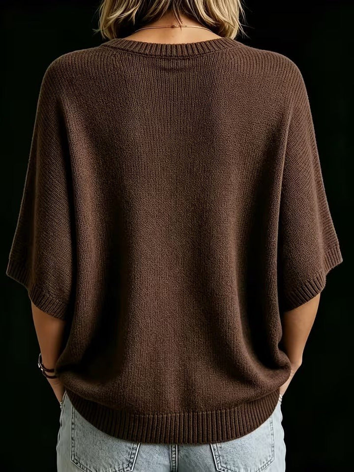Rückansicht des braunen Strickoberteils mit Fledermausärmeln und Rippbündchen am Rundhalsausschnitt, getragen zu heller Jeans. 21