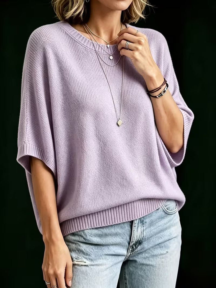 Dreiviertelansicht des fliederfarbenen Strickoberteils mit Rundhals und gerippten Bündchen, kombiniert mit heller Jeans. 8