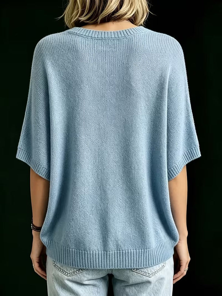 Rückansicht des hellblauen Strickoberteils mit Rundhalsausschnitt, gerippten Ärmelabschlüssen und Saum, getragen mit heller Jeans. 14