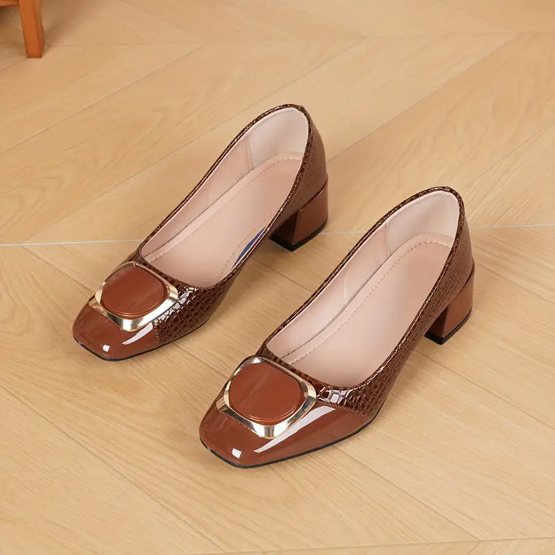 Paar braune Pumps mit goldener Schnalle auf Holzboden liegend, die helle gepolsterte Innensohle und der Blockabsatz sind gut zu sehen. 4