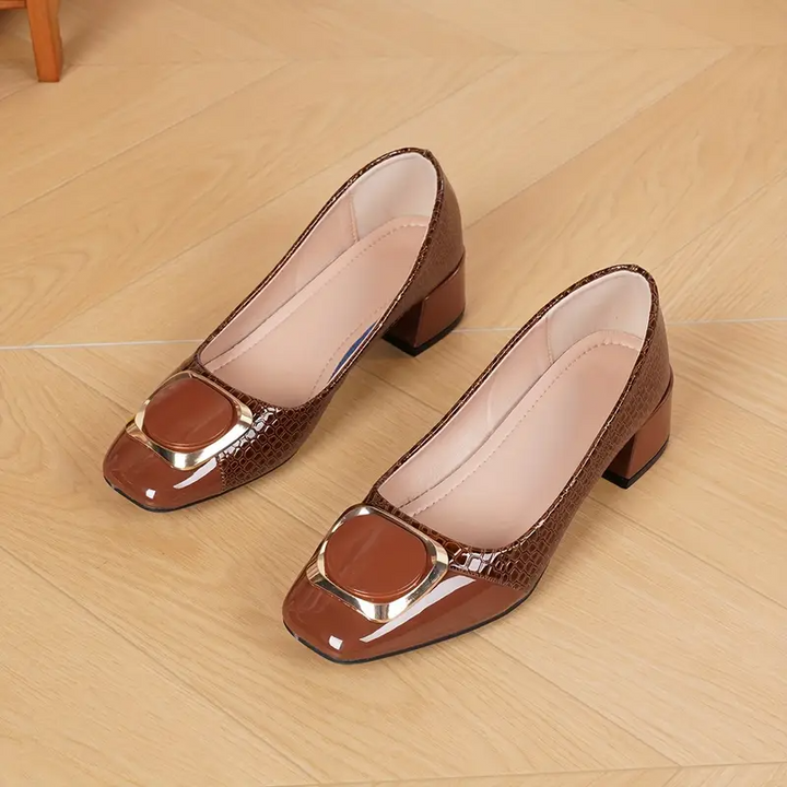 Paar braune Pumps mit goldener Schnalle auf Holzboden liegend, die helle gepolsterte Innensohle und der Blockabsatz sind gut zu sehen. 4