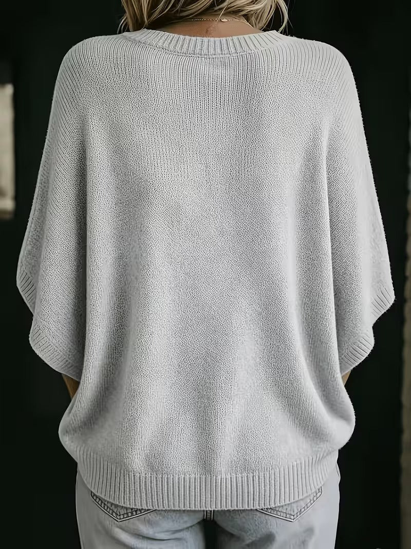 Rückansicht des hellgrauen Strickoberteils mit Rundhalsausschnitt, gerippten Ärmelbündchen und Saum, getragen mit heller Jeans. 3