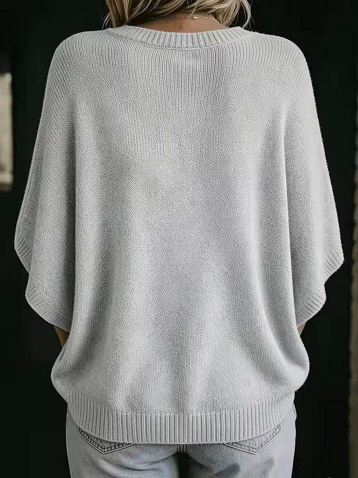 Rückansicht des hellgrauen Strickoberteils mit Rundhalsausschnitt, gerippten Ärmelbündchen und Saum, getragen mit heller Jeans. 3