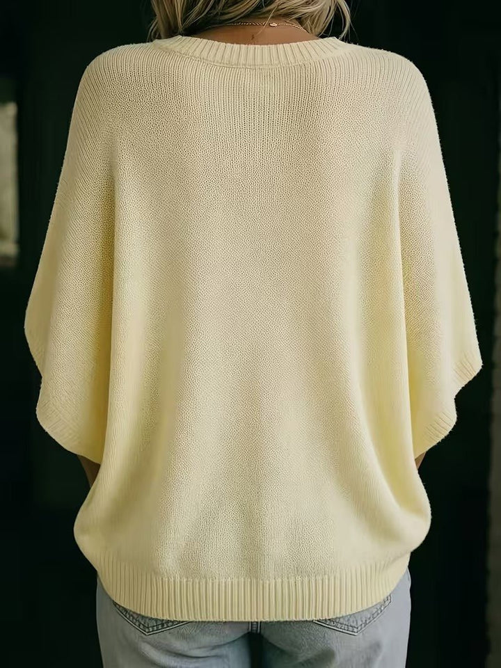 Rückansicht des hellgelben Strickoberteils mit gerippten Bündchen an Ausschnitt, Ärmeln und Saum, getragen mit heller Jeans. 6