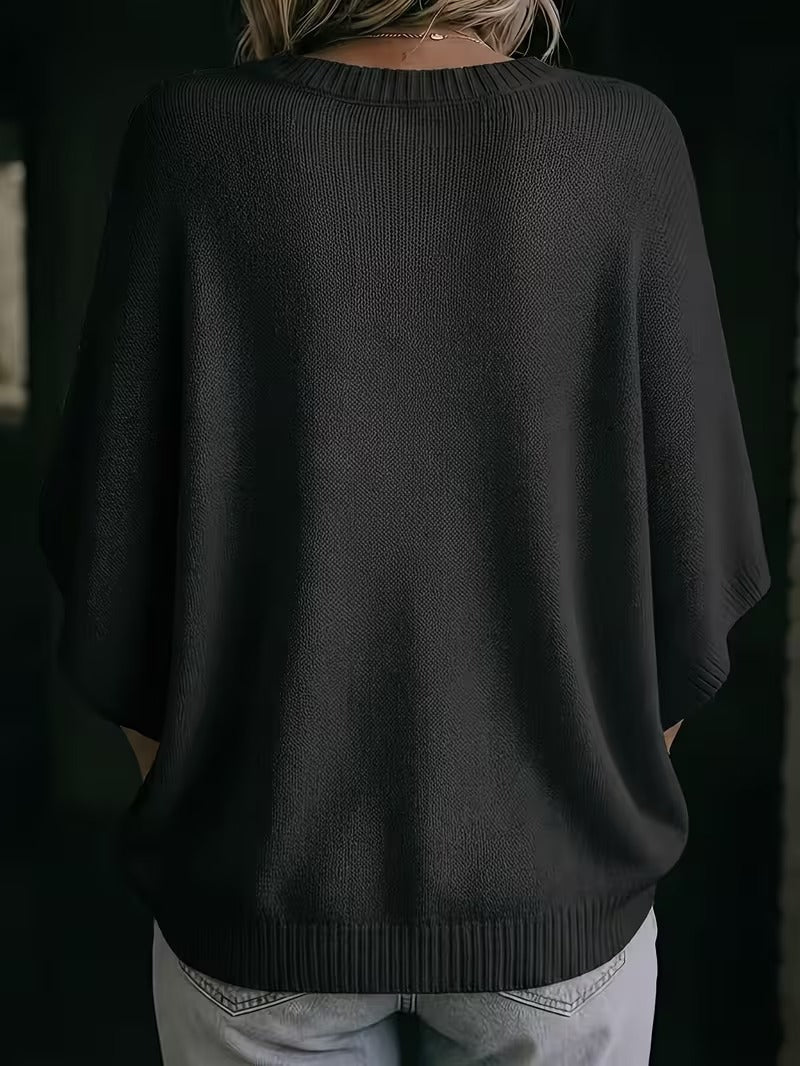 Rückansicht des schwarzen Strickoberteils mit weit geschnittenen Fledermausärmeln und Rippsaum, getragen zu heller Jeans. 28