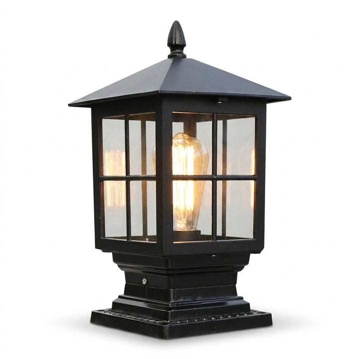 Freisteller der schwarzen Pfostenleuchte mit Glasfeldern, Dachspitze und leuchtender Filamentlampe auf weißem Hintergrund, in leichter Schrägansicht. 1