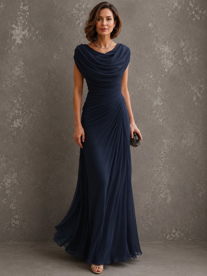 Frontansicht in Marineblau: Model im ärmellosen Kleid mit drapiertem Ausschnitt und seitlich gerafftem Oberteil, den bodenlangen Rock leicht schwingend. 2