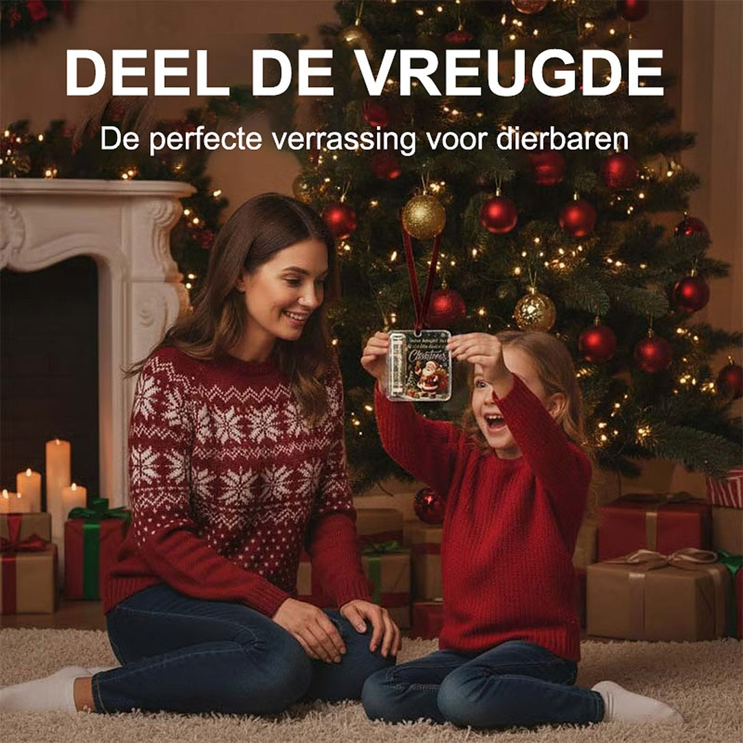 Mädchen im roten Pullover hält den Anhänger mit Geldrolle hoch, die Mutter sitzt lächelnd neben ihr vor dem Weihnachtsbaum. 3