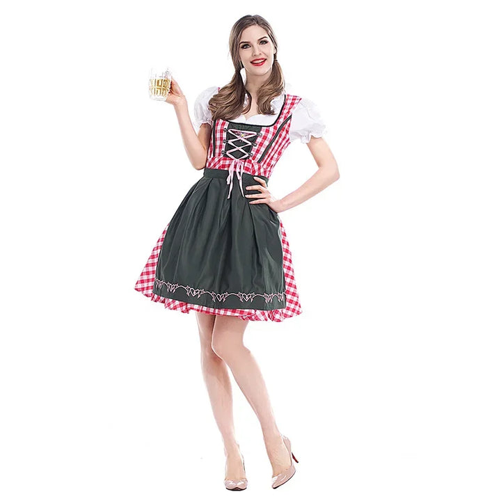 Frau im Dirndl mit rot-weiß kariertem Mieder, dunkelgrüner Schürze und weißer Puffärmelbluse hält einen Bierkrug in der Hand. 1