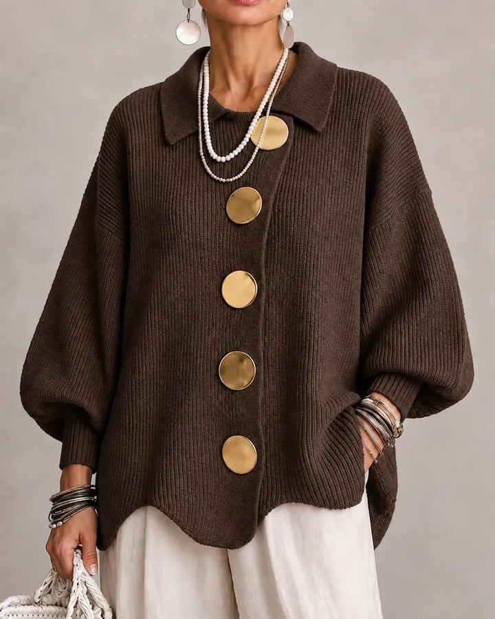 Strickjacke in Dunkelbraun mit goldfarbenen Knöpfen, getragen zu weißer Hose, Perlenketten und Armreifen. 9