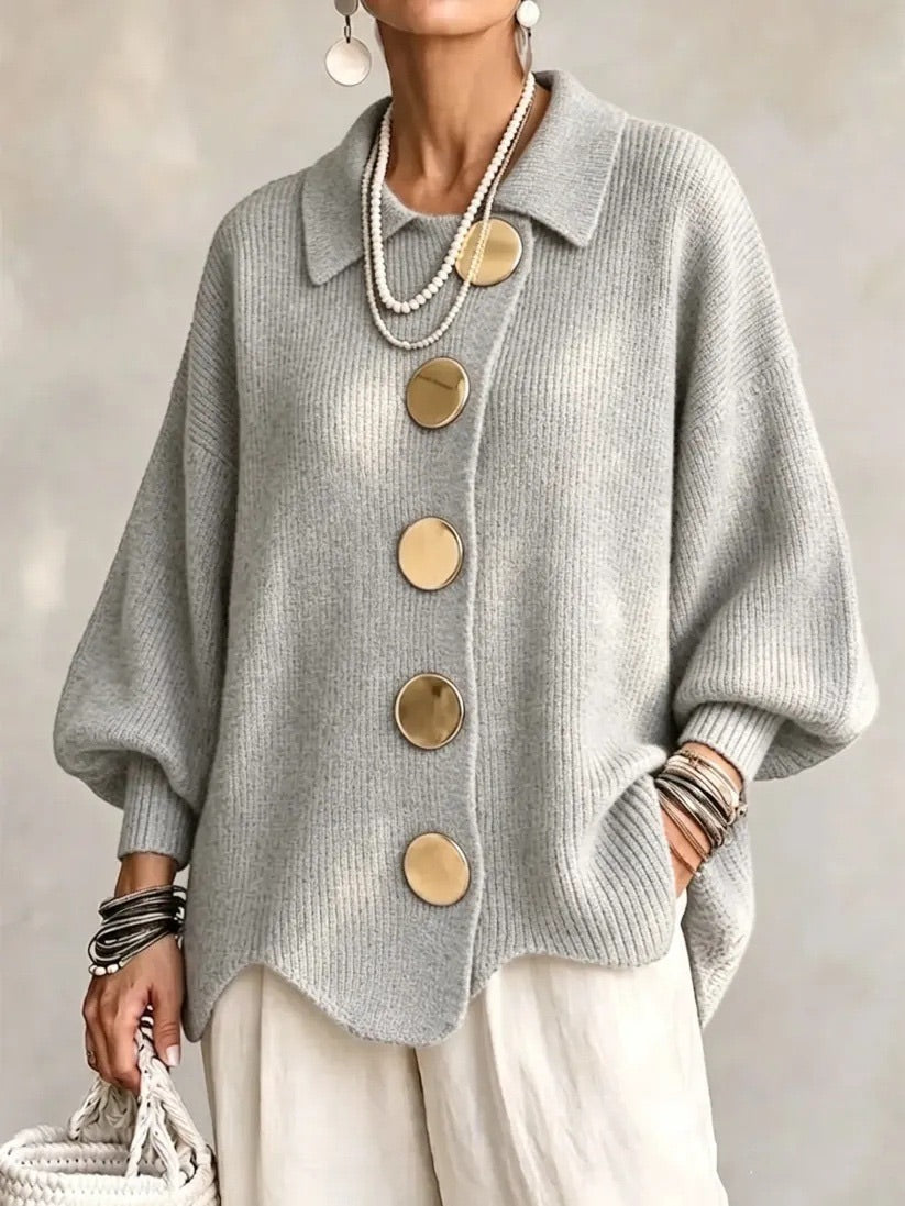 Strickjacke in meliertem Hellgrau mit goldfarbenen Knöpfen und gewelltem Saum, getragen zu heller Hose, Frontansicht. 10
