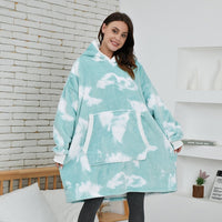 Frau in blau-weißem Oversize-Hoodie mit Wolkenmuster, gemütliche Kleidung, Wohnzimmer.