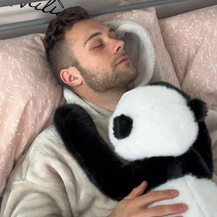 Schlafender Mann im Bett hält den Panda im Arm, dessen schwarze Arme sich über seine Brust legen. 11