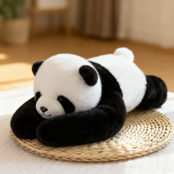 Schwarz-weißes Panda-Kuscheltier mit langen Armen liegt auf einer runden Strohmatte, flauschiges Fell in warmem Wohnzimmerlicht. 1