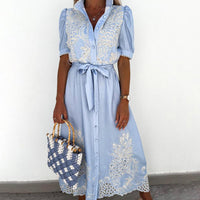 Frau in hellblauer Maxikleid mit Spitze, hält geflochtene Tasche, elegantes Sommeroutfit.