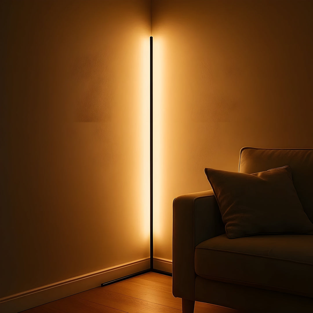 Nahaufnahme der leuchtenden Eckleuchte in der Wandecke, warmes Licht auf beiden Wänden, daneben der Rand eines Sofas mit Kissen. 3