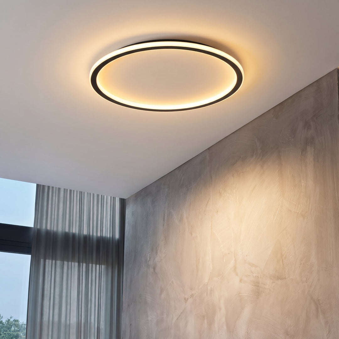 Die leuchtende Ringleuchte an einer weißen Decke neben einer Wand in Betonoptik und einem Fenster mit Vorhang. 3