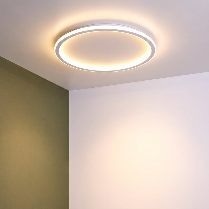 Eingeschaltete Ringleuchte an der Decke vor einer olivgrünen und einer weißen Wand in der Raumecke. 10