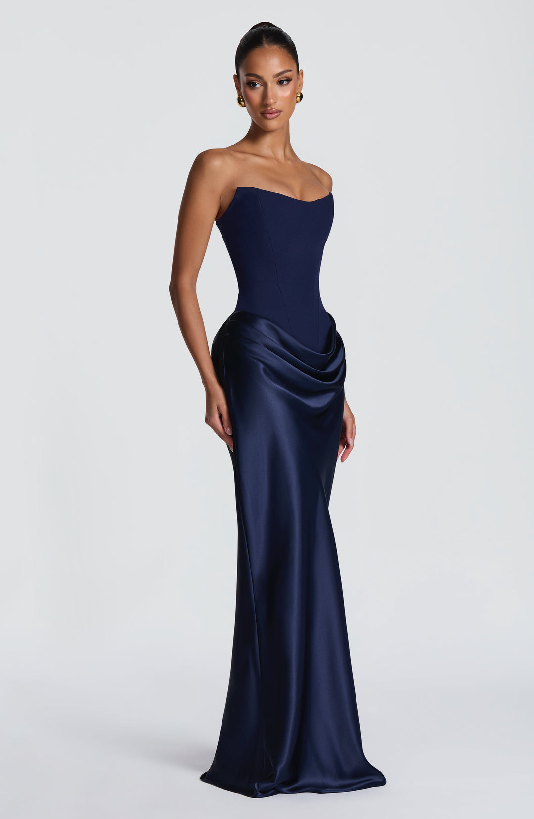 Model im marineblauen Maxikleid, leicht seitlich gedreht, mit glänzendem Satinrock und Wasserfalldrapierung an der Hüfte 43