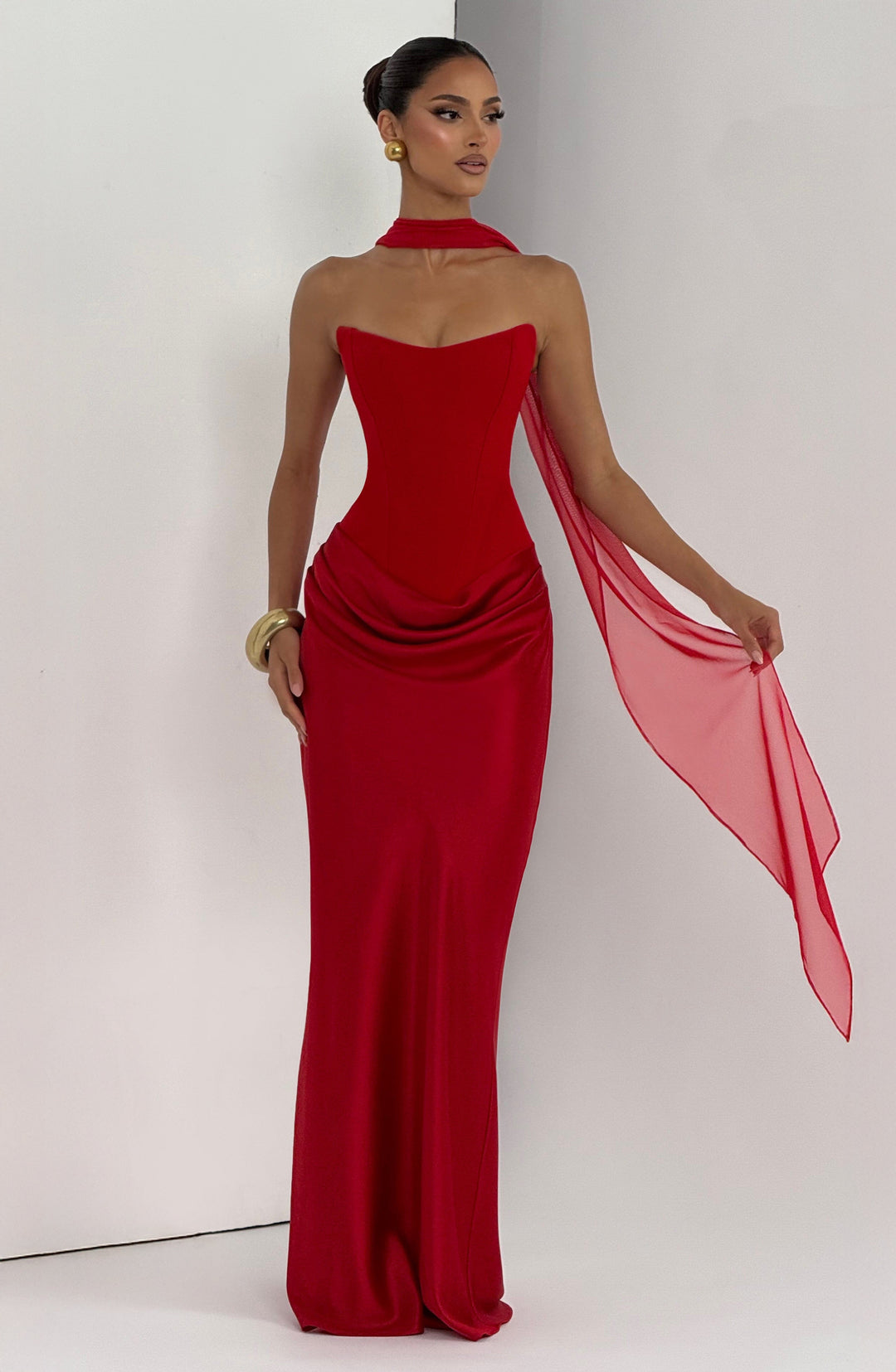 Model in rotem Kleid mit Halsband und lang herabfallendem Schal, goldener Armreif am Handgelenk 19