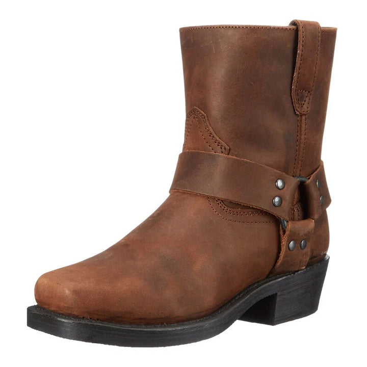 Brauner Lederstiefel in Schrägansicht von vorn mit Schnallenriemen, Nieten, eckiger Spitze und kräftigem Absatz. 1
