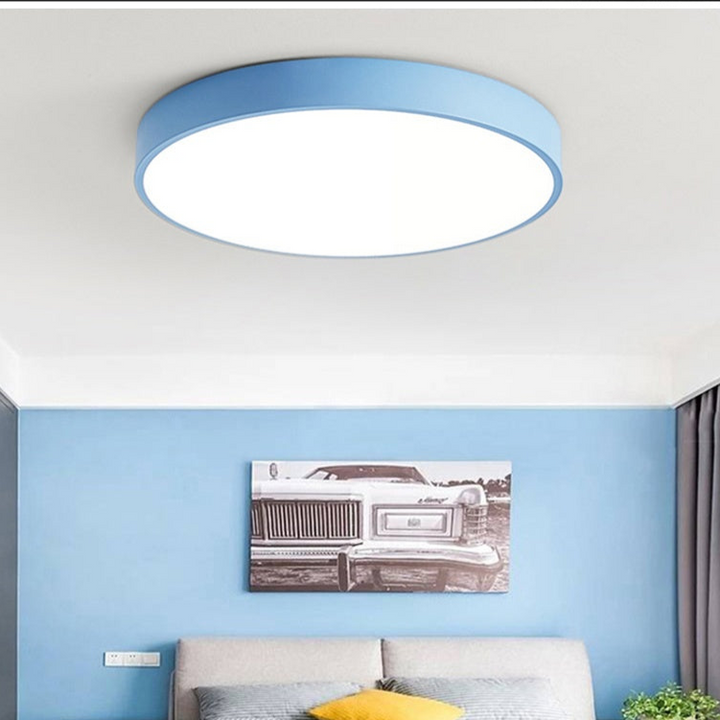 Hellblaue runde Deckenleuchte ohne Holzteil in einem Zimmer mit blauer Wand, Bett und Autobild darüber. 4