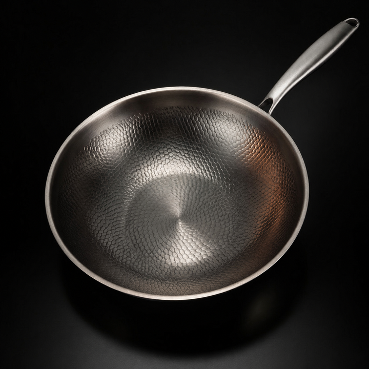 Draufsicht in die leere Pfanne, die das gleichmäßige Hammerschlagmuster der Innenfläche und den langen Metallgriff zeigt. 2