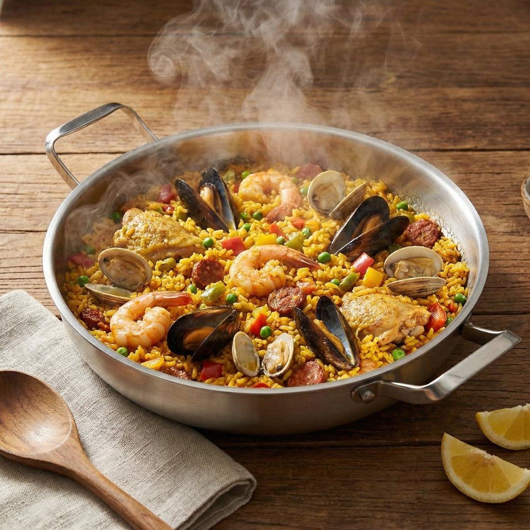 Dampfende Paella mit Garnelen, Muscheln, Hähnchen und Chorizo in der Pfanne auf einem Holztisch, daneben Zitronenspalten und Holzlöffel. 7