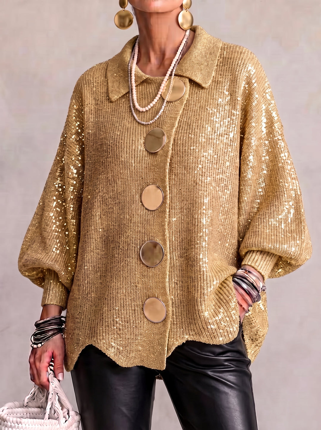 Strickjacke in Gold mit Pailletten, getragen zu schwarzer Lederhose und großen goldenen Ohrringen, Frontansicht. 3