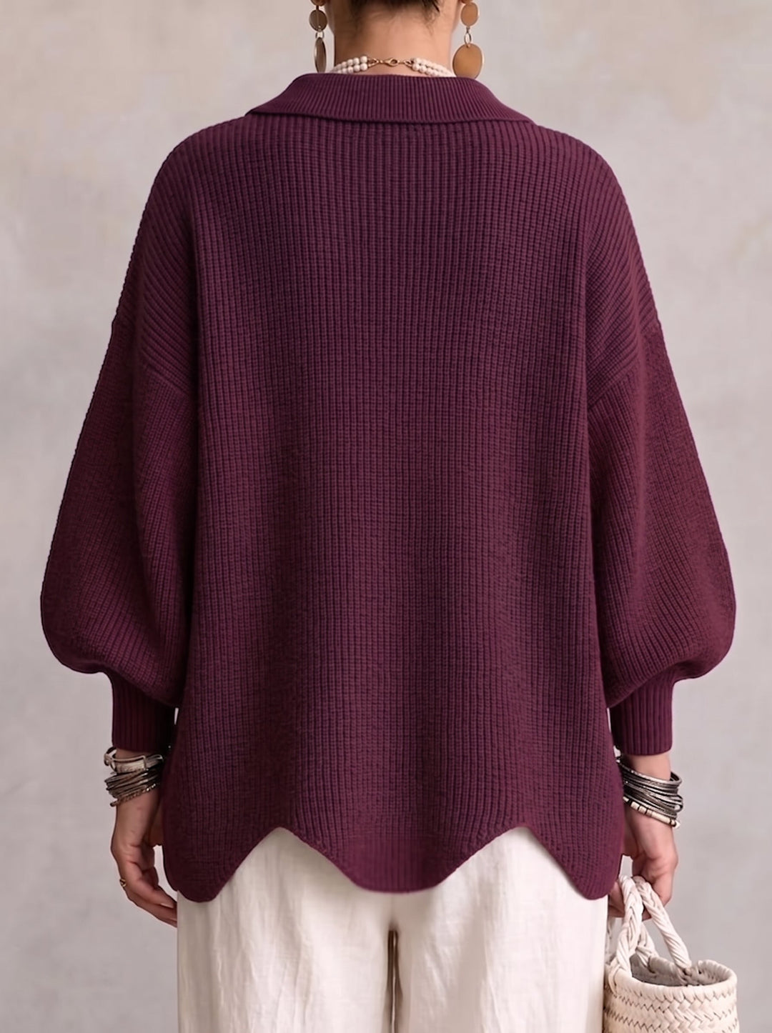 Rückansicht der Strickjacke in Beerenviolett mit Kragen, weiten Ärmeln und gewelltem Saum, getragen zu weißer Hose. 15