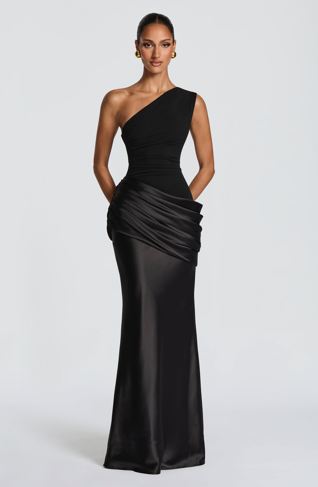 Frau im schwarzen One-Shoulder-Maxikleid mit glänzendem Satinrock und gerafftem Hüftdrapé, goldene Ohrringe, frontale Ganzkörperansicht. 20