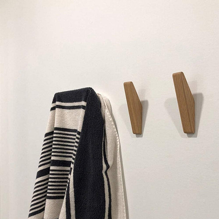 Zwei Holzhaken an einer weißen Wand, an einem hängt ein schwarz-weiß gestreiftes Handtuch, der andere bleibt frei. 4