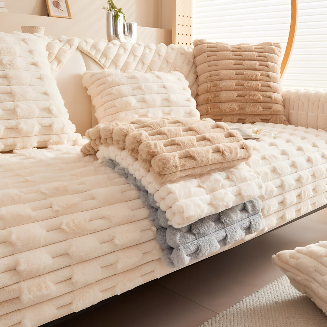 Sofa mit cremefarbener Hussen-Auflage, davor gestapelt die Farben Beige, Creme und Grau als Farbauswahl, dazu passende Kissen. 7