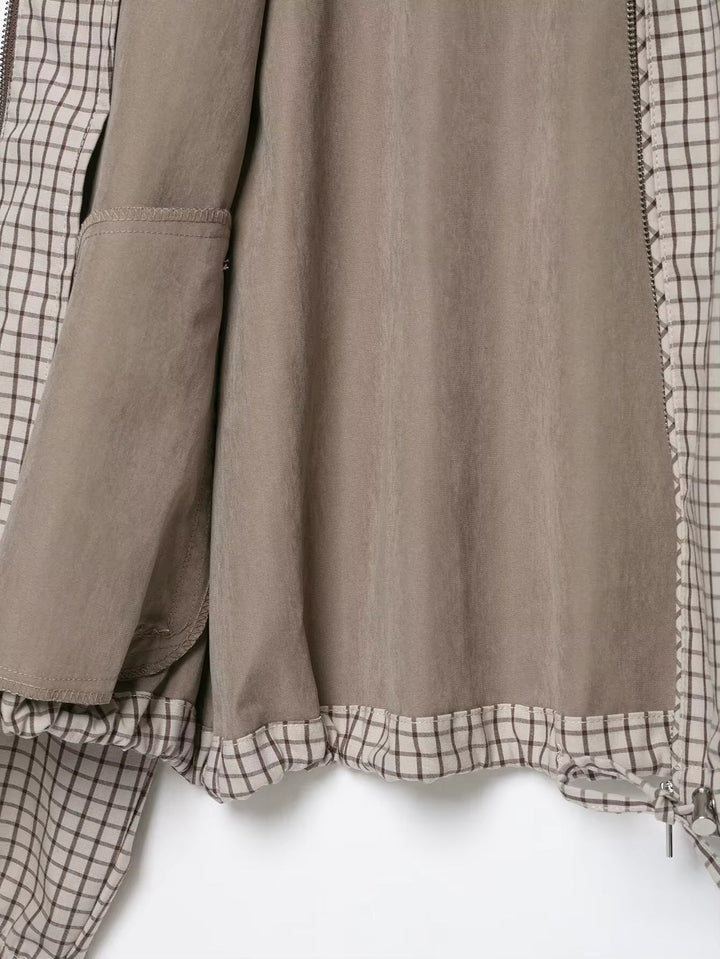 Flach ausgebreitetes Innenfutter der Jacke in Taupe mit Innentasche, karierter Blende am Saum und Kordelzug mit Metallenden. 5